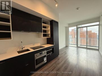 Toronto (Bay Street Corridor) condo for rent - A modern kitchen with dark wood cabinets and a stainless steel oven.