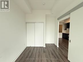 Toronto (Bay Street Corridor) condo for rent - A room with white walls and wooden flooring, with a door on the left and a hallway on the right.
