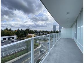 Surrey apartment for rent - A balcony overlooks a busy street with cars and buildings.