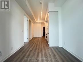 Toronto (Moss Park) condo for rent - A long hallway with wood flooring and white walls.
