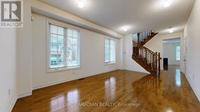 Whitchurch-Stouffville (Stouffville) apartment for rent - A spacious room with wooden floors and a staircase.