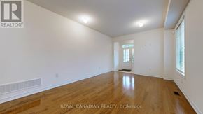 Whitchurch-Stouffville (Stouffville) apartment for rent - A spacious room with wooden flooring and white walls, with a window and a door visible.