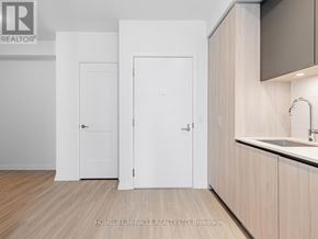 Toronto (Waterfront Communities) condo for rent - A white door is in a room with wooden floors and a counter.