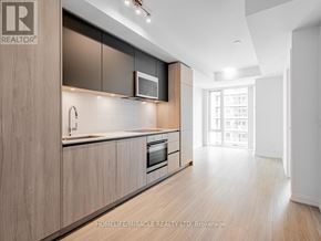 Toronto (Waterfront Communities) condo for rent - A modern kitchen with wooden cabinets and a microwave above the oven.