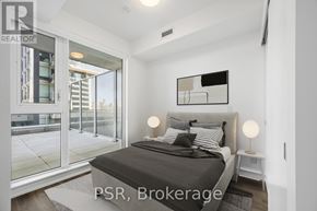 Toronto (Niagara) condo for rent - A bedroom with a large bed and a glass door leading to a balcony.