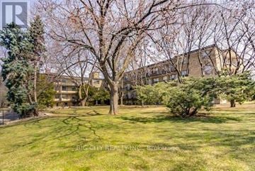 Toronto (St. Andrew-Windfields) condo for rent - A tree with no leaves stands in a grassy area in front of a building.