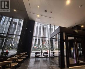 Toronto (Annex) condo for rent - A view of the lobby of a building with a glass wall and chairs.