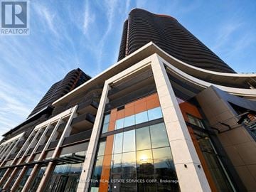 Toronto (Bayview Village) condo for rent - A modern building with a curved glass facade and a sunset in the background.