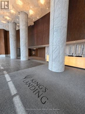 Toronto (Bayview Village) condo for rent - A carpet with the words "King's Landing" on it is in the foreground of a room with pillars and wooden walls.
