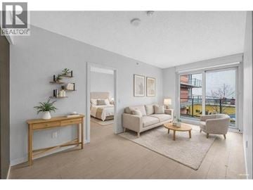 Vancouver apartment for rent - A living room with a white couch, a wooden table, and a large window.