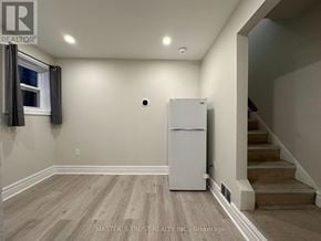 Toronto (Caledonia-Fairbank) apartment for rent - A white refrigerator is in a room with wooden floors and a staircase.