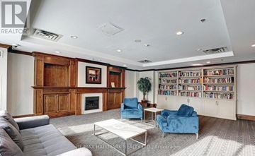 Richmond Hill (Langstaff) condo for rent - A living room with a grey sofa, a blue armchair, a glass coffee table and a bookshelf filled with books.