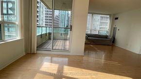 Toronto (Willowdale East) condo for rent - A spacious living room with wooden floors and a large window overlooking a balcony.