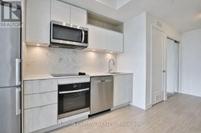 Toronto (Moss Park) condo for rent - A modern kitchen with stainless steel appliances and white cabinets.