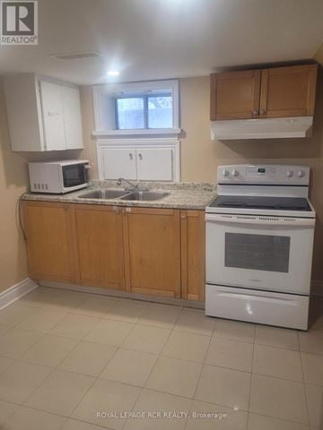 Newmarket (Bristol-London) apartment for rent - A kitchen with a white oven and microwave, and wooden cabinets.