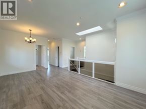 Vancouver apartment for rent - A spacious room with wooden flooring and a chandelier.