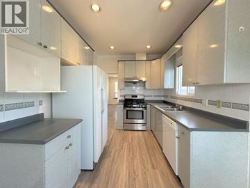 Vancouver apartment for rent - A modern kitchen with white cabinets and a wooden floor.