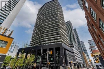 Toronto (Waterfront Communities) condo for rent - A tall building with a curved facade stands in front of other buildings.
