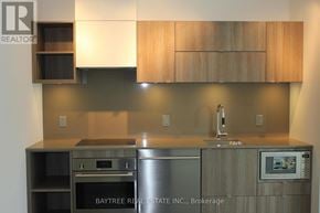 Toronto (Waterfront Communities) condo for rent - A modern kitchen with wooden cabinets and stainless steel appliances.