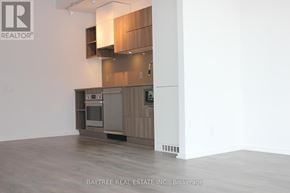 Toronto (Waterfront Communities) condo for rent - A modern kitchen with wooden cabinets and a stainless steel oven.