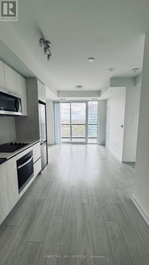 Toronto (Newtonbrook West) condo for rent - A spacious kitchen with a microwave above the stove and a view of the backyard through the open door.