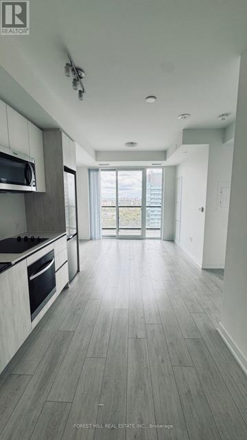 Toronto (Newtonbrook West) condo for rent - A spacious kitchen with a microwave above the stove and a view of the backyard through the open door.