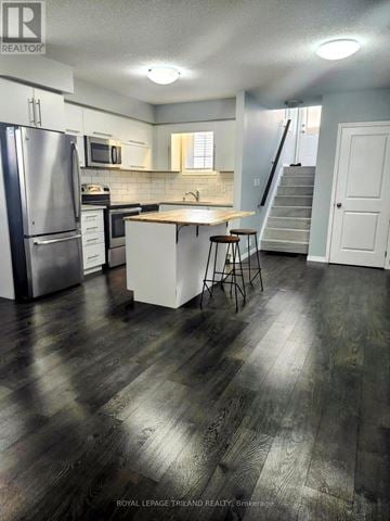 London South (South W) townhouse for rent - A kitchen with a refrigerator, stove, and bar stools.