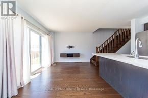 Clarington (Bowmanville) townhouse for rent - A spacious living room with a staircase and a flat screen TV.