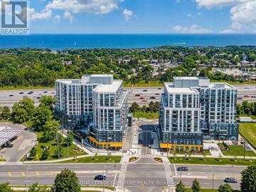 Toronto (Rouge) condo for rent - A large, modern building complex with a glass facade is situated in a parking lot with a view of the ocean in the distance.