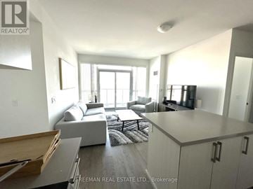 Mississauga (Central Erin Mills) condo for rent - A well-lit, modern living room with a grey sofa and a wooden coffee table.