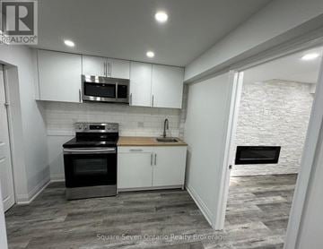 Brampton (Bram East) apartment for rent - A kitchen with a stove top oven and microwave above a counter.