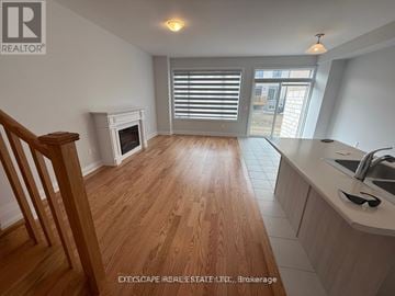Kawartha Lakes (Lindsay) townhouse for rent - A wooden floor leads to a kitchen area with a sink and a window.