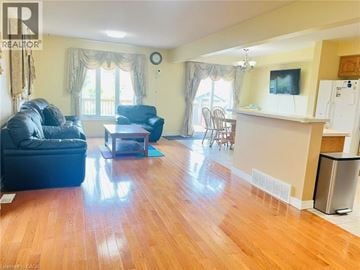 Kitchener apartment for rent - A living room with a black leather couch and a wooden floor.