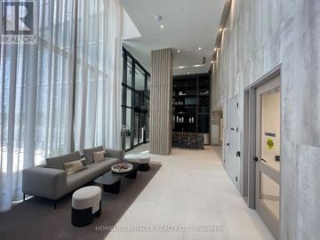 Vaughan (Steeles West Industrial) condo for rent - A modern living room with a grey sofa and a glass door leading to a wine cellar.