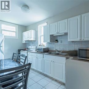 Hamilton apartment for rent - A kitchen with white cabinets and a table with chairs.