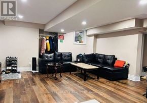 Brampton (Toronto Gore Rural Estate) apartment for rent - A living room with a black leather couch and a wooden floor.
