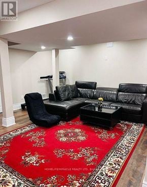 Brampton (Toronto Gore Rural Estate) apartment for rent - A black leather couch and chair with a red floral rug in front of them.