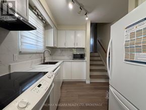 Welland (N. Welland) apartment for rent - A kitchen with white cabinets and a stove top oven.