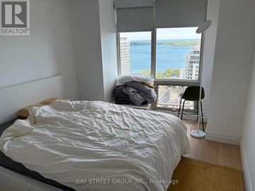 Toronto (Waterfront Communities) condo for rent - A bedroom with a large bed and a view of the water.