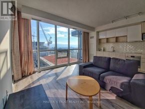 Toronto (Henry Farm) condo for rent - A living room with a couch, a table, and a view of a construction site through the windows.