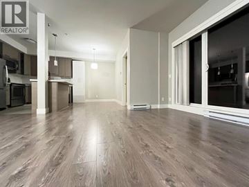Burnaby apartment for rent - A spacious living room with wood flooring and a kitchen area in the background.