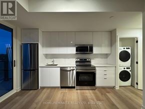 Brantford condo for rent - A modern kitchen with stainless steel appliances and white cabinets.