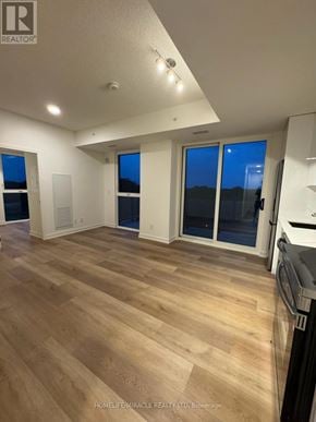 Brantford condo for rent - A well-lit, spacious kitchen and living room with wooden flooring and large windows.