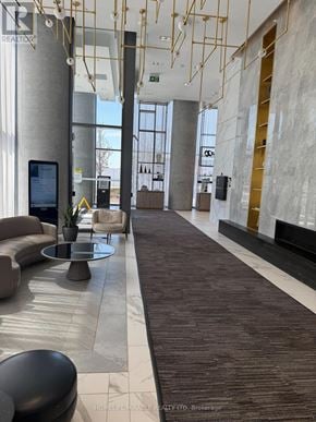 Vaughan (Vaughan Corporate Centre) condo for rent - A modern lobby with a long carpeted hallway and a large screen on the left.