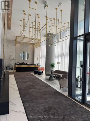 Vaughan (Vaughan Corporate Centre) condo for rent - A modern lobby with a reception desk and a large mirror.