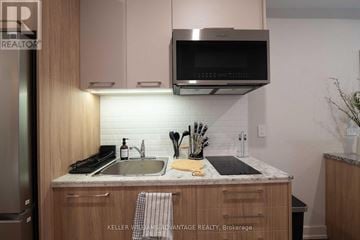 Toronto (Kensington-Chinatown) apartment for rent - A modern kitchen with wooden cabinets and a stainless steel range hood.