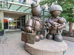 Toronto (Waterfront Communities) condo for rent - A statue of a man holding a suitcase and a woman holding a baby is in front of a building.