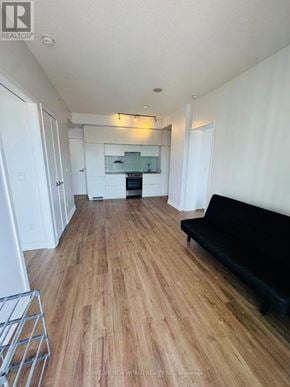Toronto (Church-Yonge Corridor) condo for rent - A black sofa sits in a living room with wood flooring and white walls.