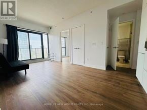 Toronto (Church-Yonge Corridor) condo for rent - A spacious room with wooden floors and white walls.
