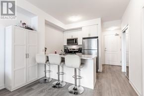 Hamilton (Waterdown) condo for rent - A kitchen with white cabinets and a bar area with stools.